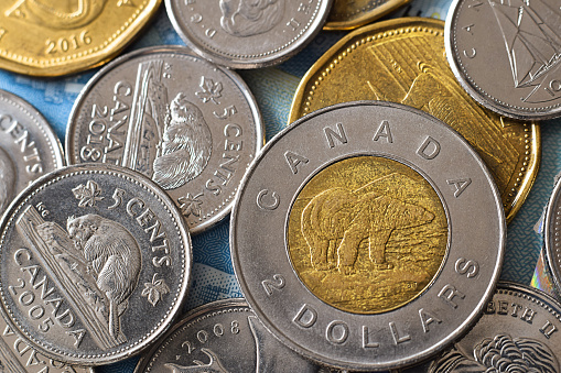 Large stack of international coins against a grey background.