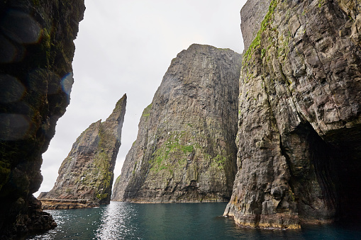 Stunning green cliffs and cave on atlantic ocean in Faroe islands.