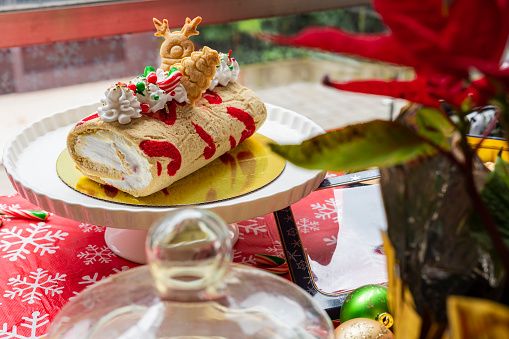 Table decorated with a Christmas theme, a red tablecloth with small snowflakes has delicious dishes on top to celebrate these dates, with Christmas cookies, delicious desserts with green, red and gold colors
