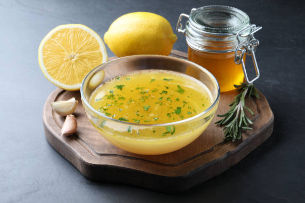 istock Bowl with lemon sauce and ingredients on dark table. Delicious salad dressing 1441947344