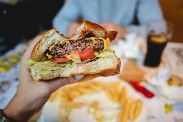 istock Hands holding fresh delicious burger. half of hamburger in a hands. 1441947484