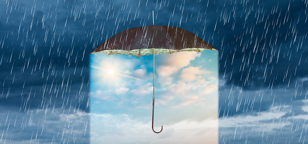 Concept of storm and heavy rain with a vintage umbrella revealing a blue sky with shining sun