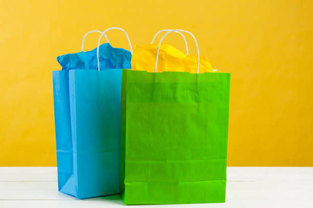 istock Paper shopping bags on bright yellow background 1441950471