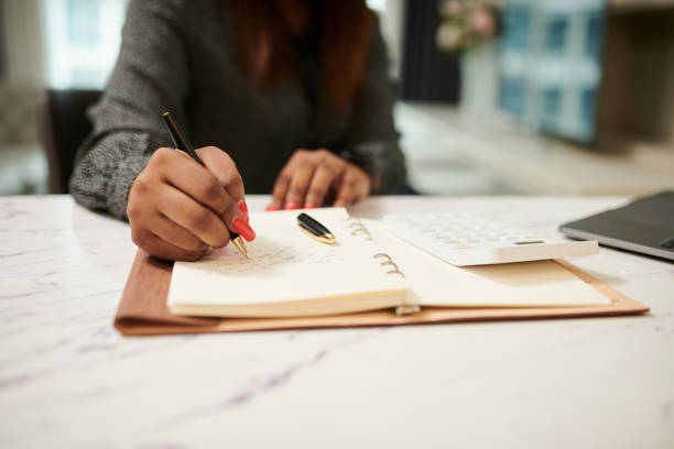 istock Businesswoman Writing in Planner 1441955153
