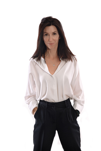 Woman in a white shirt and balck trousers stands in front of white background