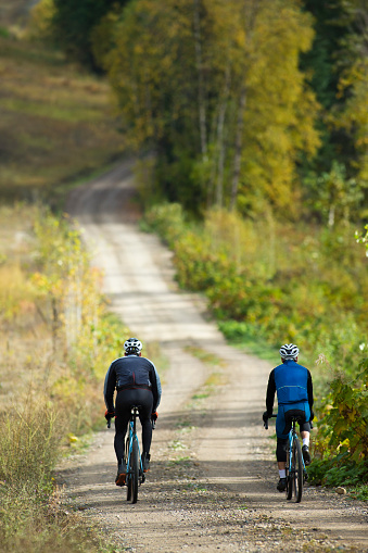 Two men go for a gravel bicycle ride in October. Gravel bikes are similar to road bikes but have oversized tires for riding on rough terrain.