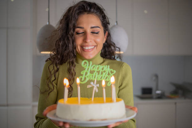 istock Woman blowing out birthday cake candles 1441960910