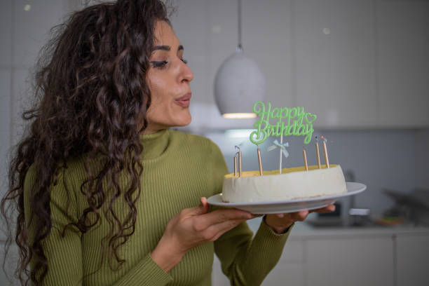 istock Woman blowing out birthday cake candles 1441960973