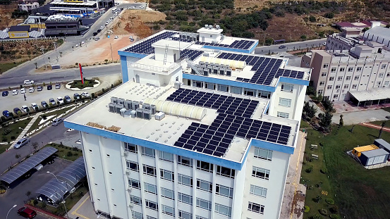 Top view of roof of white building with solar panels. Clip. Modern equipping of buildings with eco-friendly electricity using solar panels on roof.