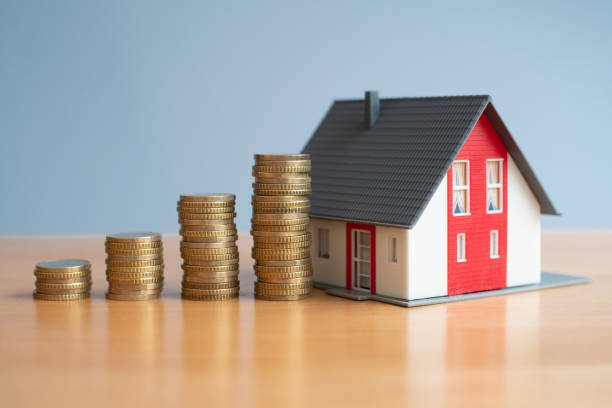 istock Ascending stacks of coins next to a model home 1441962326