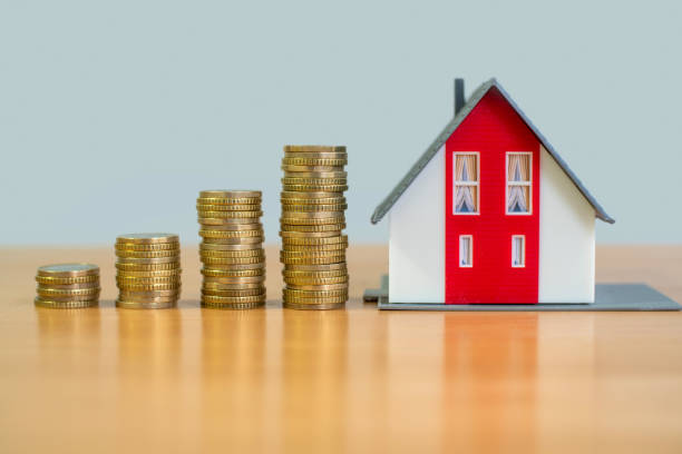 Ascending stacks of coins next to a model home