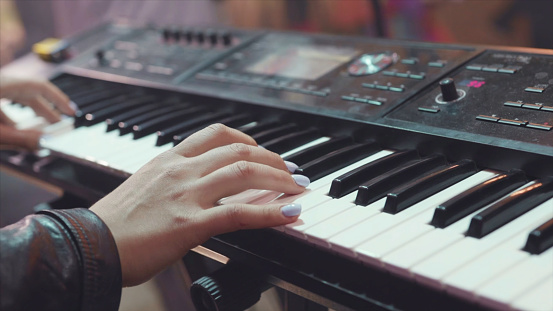 MIDI keyboard synthesizer piano keys. Stock. Woman playing the synthesizer. A music instrument background, music concept.