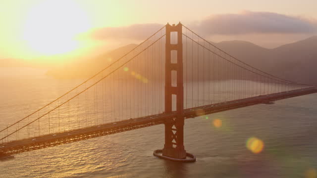AERIAL Golden Gate Bridge with sun setting behind Marin Headlands, California