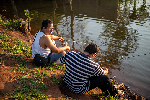 Portrait of two Brazilian friends going to fish at a lake in a public park, in a sunny afternoon.
