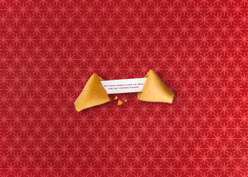 A funny image of a fortune cookie on a red background with the fortune reading 