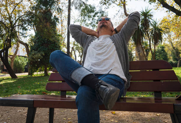 man relaxing sitting on a bench in a park
