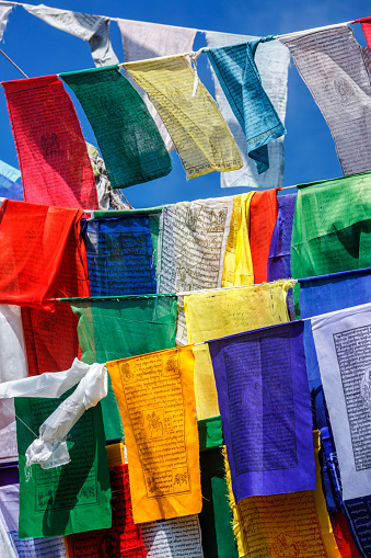 Buddhist prayer flags lungta with Om Mani Padme Hum Buddhist mantra prayer meaning Praise to the Jewel in the Lotus on kora around Tsuglagkhang complex. McLeod Ganj, Himachal Pradesh, India
