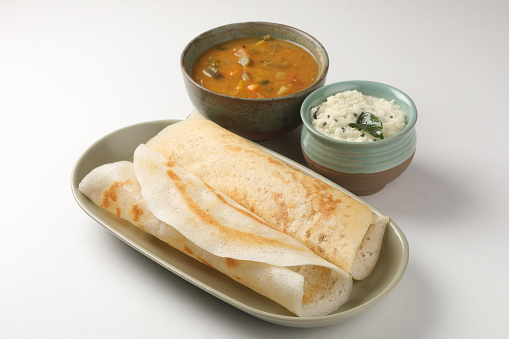 south Indian masala dosa with green chutney and sambhar on a white plate.