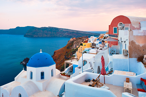 Famous view from viewpoint of Santorini Oia village with blue dome of whitewashed greek orthodox Christian church of traditional greek architecture. Oia town, Santorini island, Greece