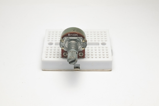 A variable resistor or potentiometer with code B10K sticks to a small project board front view on a white background.