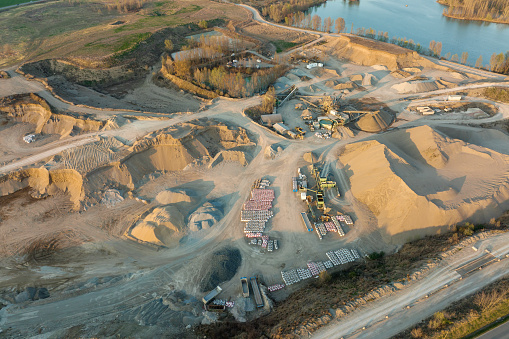 Aerial view of open pit mine of sandstone materials for construction industry with excavators and dump trucks. Heavy equipment in mining and production of useful minerals concept.