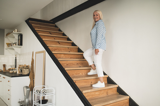 On the stairs. Good-looking blonde woman standing on the stairs