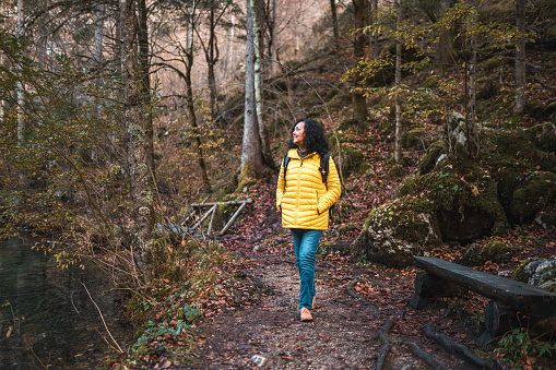 Beautiful mature Hispanic woman hiking and exploring in the mountains. She is wearing casual clothes and carrying a backpack.