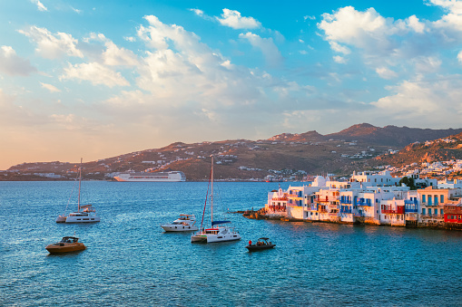 Sunset in Mykonos island, Greece with yachts in the harbor and colorful waterfront houses of Little Venice romantic spot on sunset with cruise ship and yacht boats. Mykonos townd, Greece