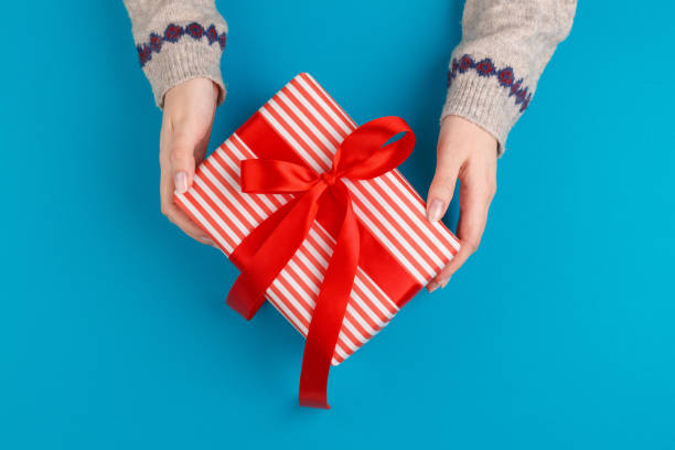 istock Small gift box in female hands on blue background, view from above 1441986660