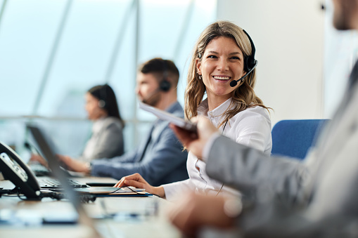 Happy businesswoman talking to her colleague while working in a call center. Copy space.