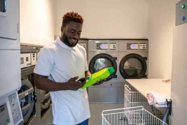 istock Pleased young man standing at a self-service launderette 1441987026