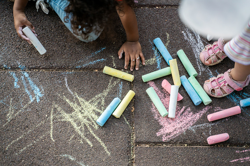 Little boy legs with sneakers and sidewalk chalks. Shallow depth of field
