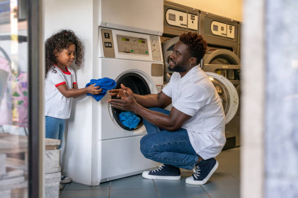 istock Man and his daughter putting laundry into a washer 1441987178