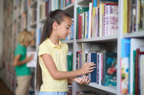 istock Girl taking a book from the shelf in the library 1441990203