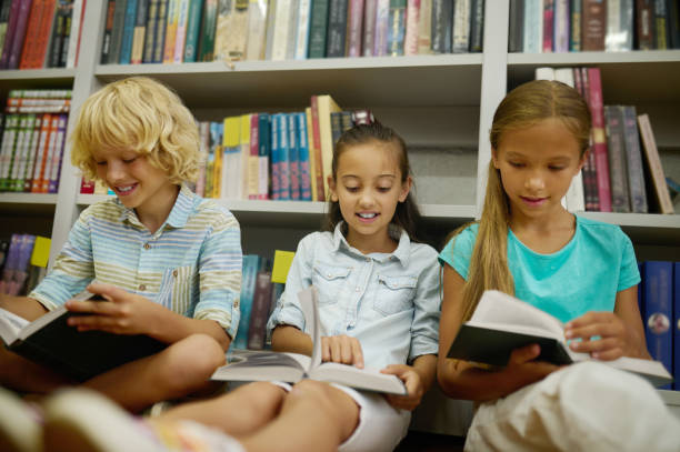istock Group of kids reading while sitting on the floor in the library 1441990276
