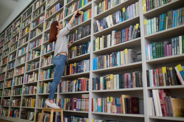 istock Young librarian searching for a book on bookshelves 1441990305