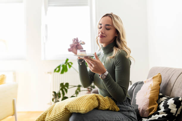 istock Young woman eating cake at home 1441996217