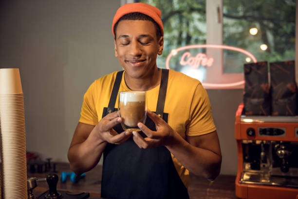 istock Pleased cafe worker smelling coffee in the glass 1441996651