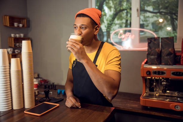 istock Young cafe worker sipping cappuccino in the workplace 1441996660