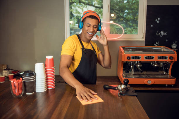 istock Joyful coffee shop worker cleaning the tabletop to music 1441996830