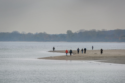 People taking an autumn walk on the beach of Travemunde on the Baltic sea on a gray November day, copy space, selected focus