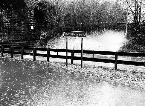 Photo of a flooded road in Dumfries as a car goes through.