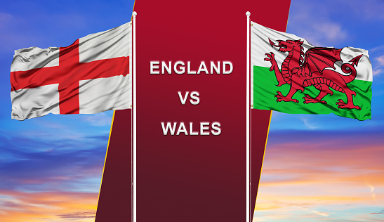 England vs. Wales two flags on flagpoles and blue cloudy sky background.Soccer matchday template