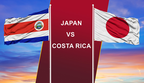 Japan vs. Costa Rica two flags on flagpoles and blue cloudy sky background.Soccer matchday template