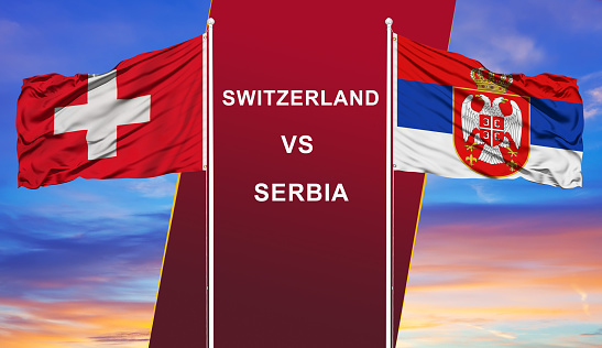 Switzerland vs. Serbia two flags on flagpoles and blue cloudy sky background.Soccer matchday template