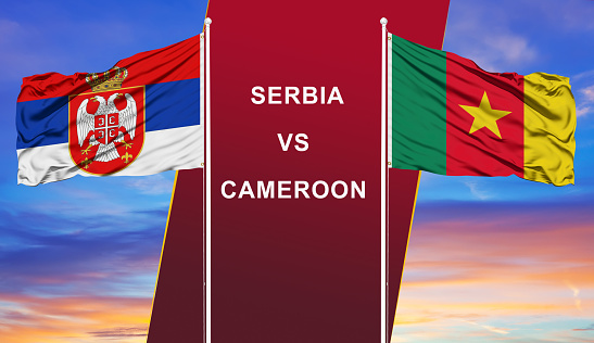 Serbia vs. Cameroon two flags on flagpoles and blue cloudy sky background.Soccer matchday template