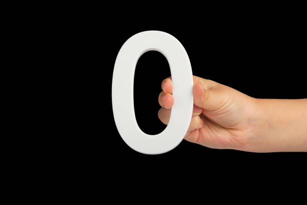 istock Zero in hand. The number zero is clasped in a hand isolated on a black background. Number zero white in a child's hand on a black background. 1442002276