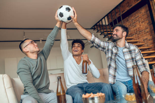 istock Three joyous friends lifting a soccer ball together 1442007027