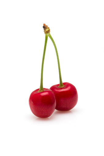 Two red cherries on a white background