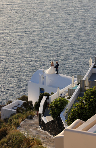 Imerovigli, Santorini, Greece - June 29, 2021: The bride and groom during a romantic photo session in Imergovigli on Santorini Island.